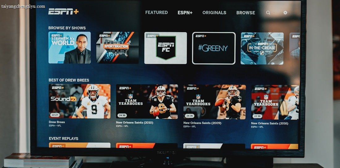A television screen displaying the ESPN+ streaming interface with various sports-related shows and categories. The screen includes sections such as 'Browse by Shows' and 'Best of Drew Brees' with thumbnails of sports programs featuring athletes in action and analysts.